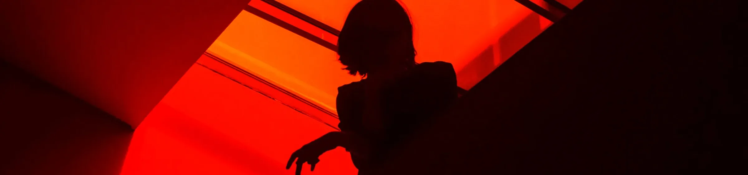 Silueta de una actriz a contraluz en una escalera iluminada en rojo